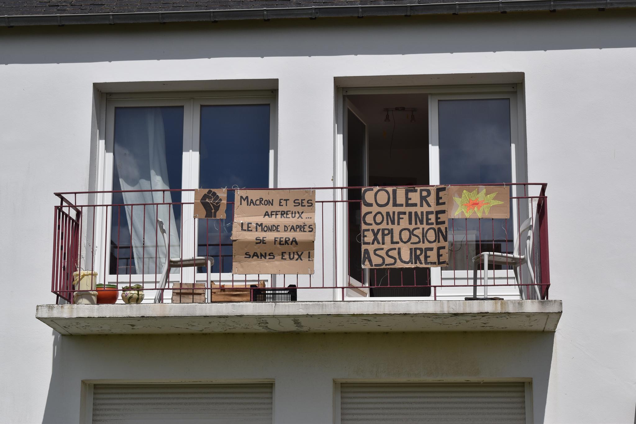 Un balcon avec des affiches en carton avec des messages politiques.